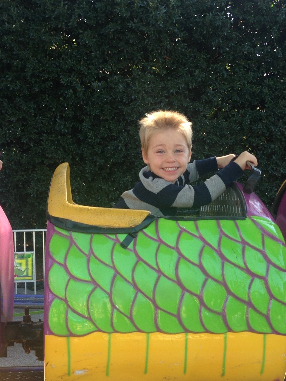 A young child smiling at the wheel of an amusement park ride